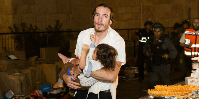 A Jewish man carries a baby injured in a stabbing attack in the Old City of Jerusalem on October 3, 2015. A Jewish family was stabbed while walking near the Lion's Gate in the Old City. The father died of his wounds. The terrorist was shot down by police. (Photo: Yonatan Sindel/Flash90)